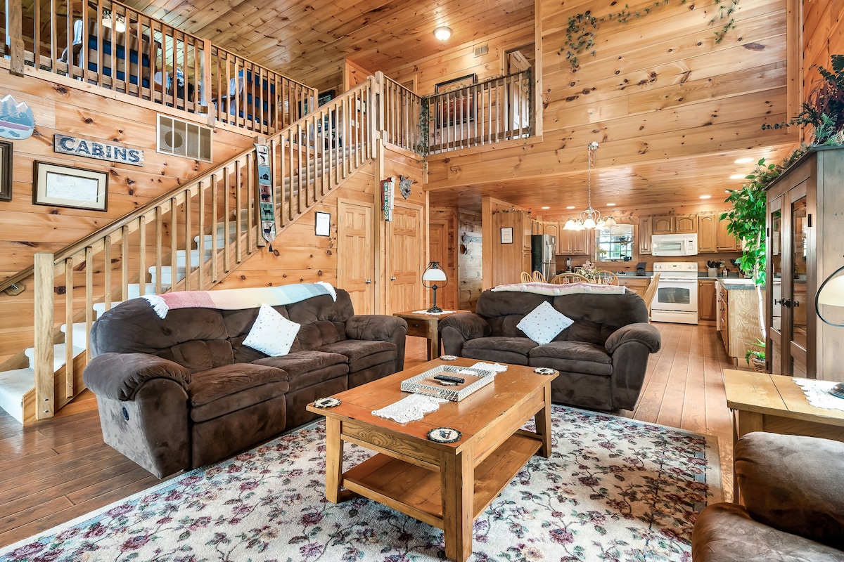 Living room with stone fireplace, timber walls and open loft